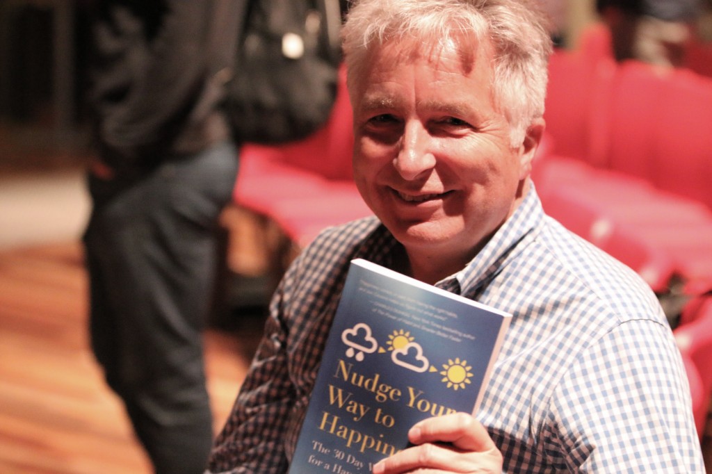 Jon holding his book "Nudge Your Way To Happiness"